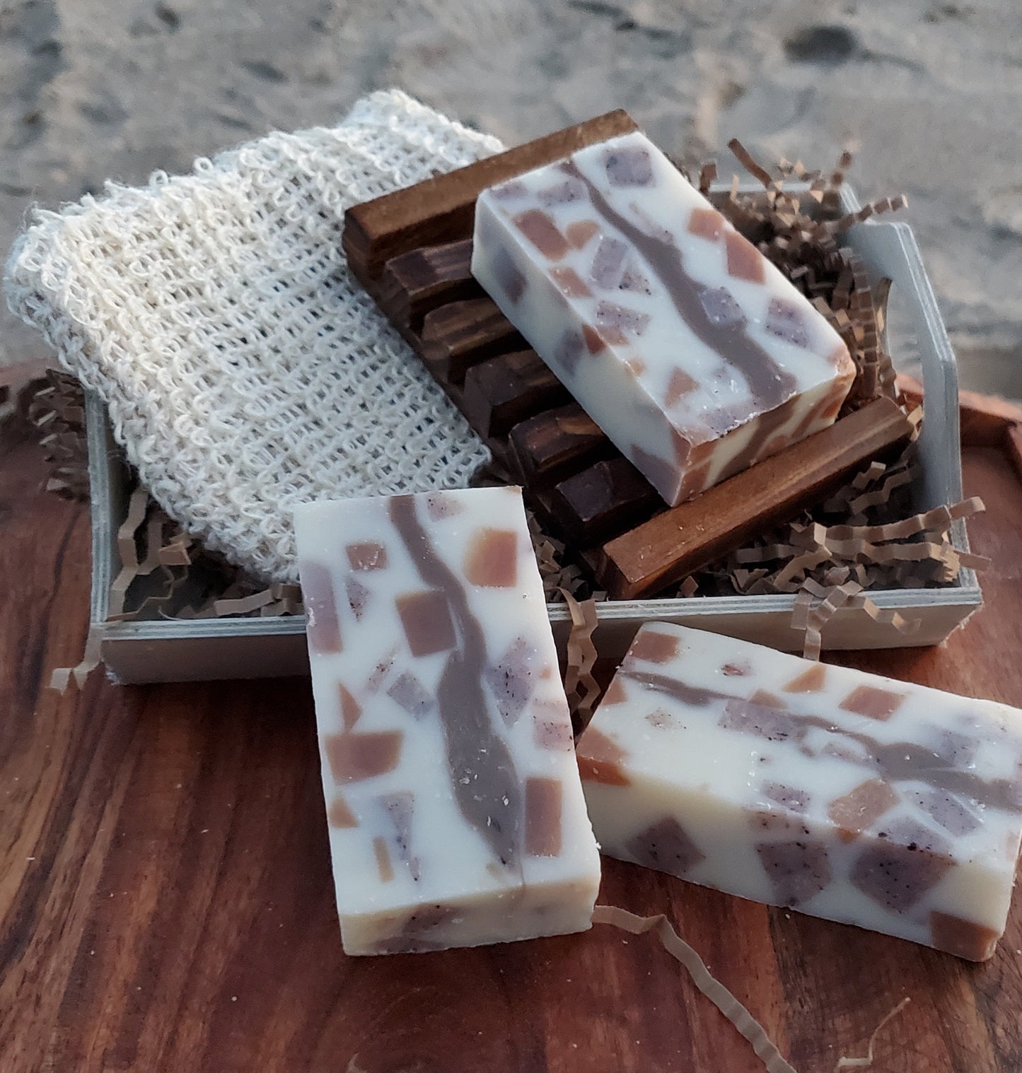 Calico All in One shampoo and body soap shown on a dark wooden soap dish on a soap bag and on a wooden tray.