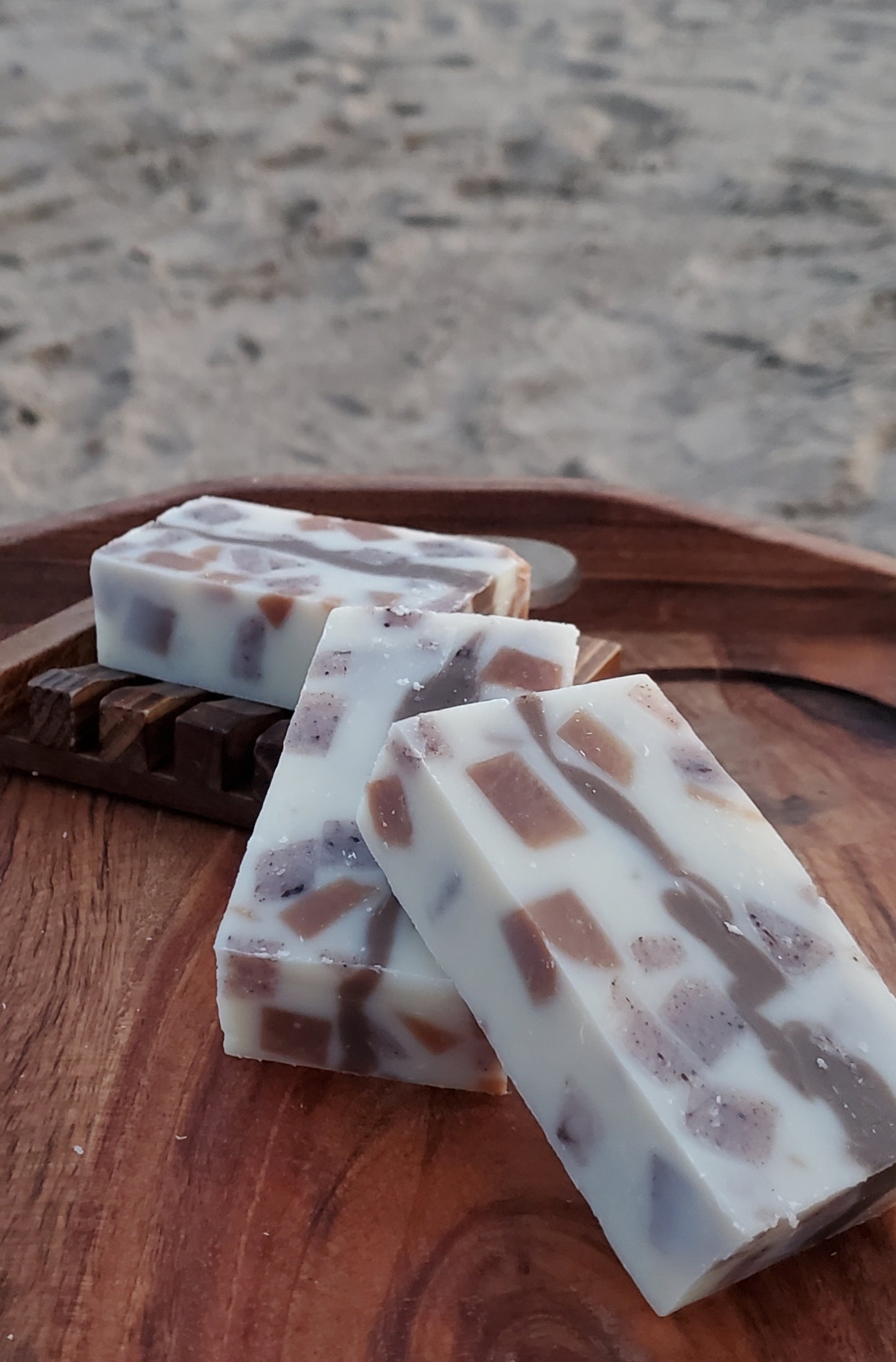 3 Calico All in One shampoo and body soap bars shown on a wooden tray, one bar is on a dark wooden soap dish.