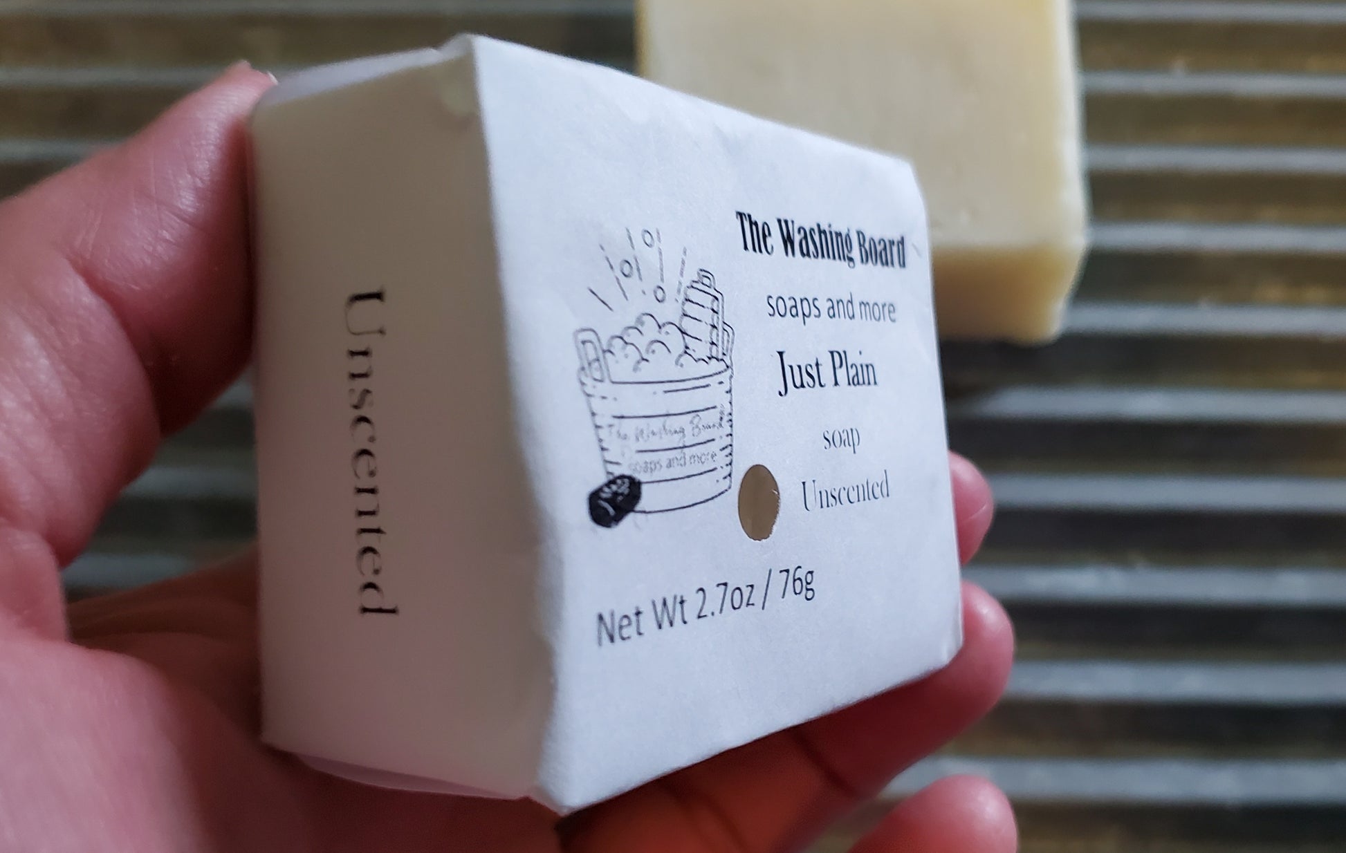 Just Plain soap shown in eco friendly packaging on an angle in a woman's hand. 