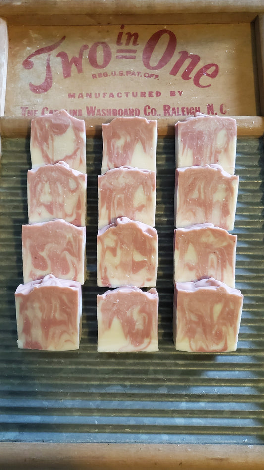 Just Plain Soap pink edition shown, tall and narrow bar,  on a washing board.  