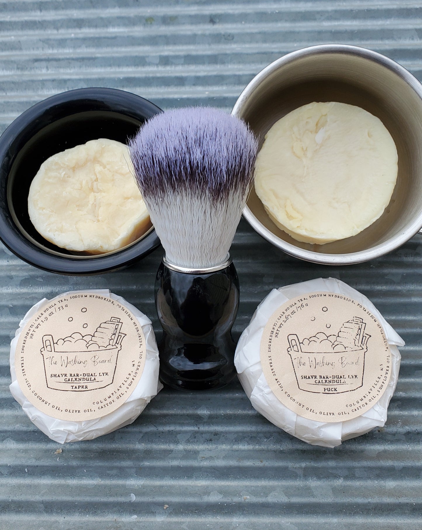 Dual Lye Shave Soaps,  "Naked" Taper in the black bowl, "naked" Puck in the stainless steel cup,  a Shave Brush, a wrapped taper and a wrapped puck.